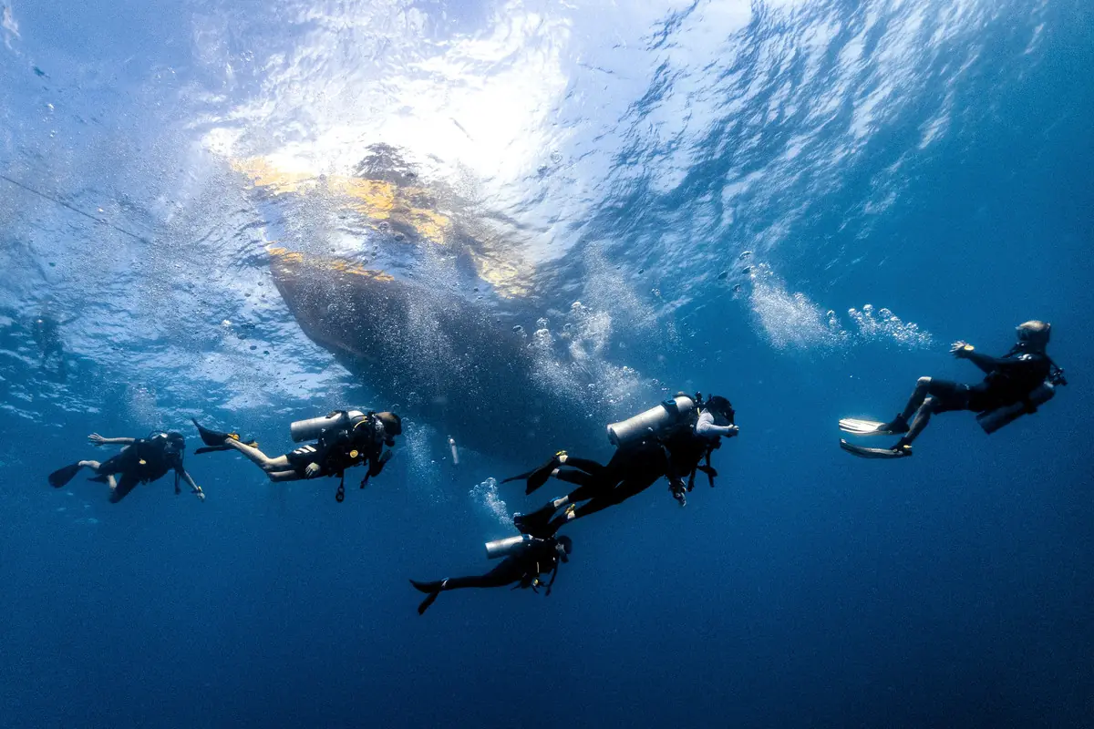 Divers hovering in open blue water under the dive boat