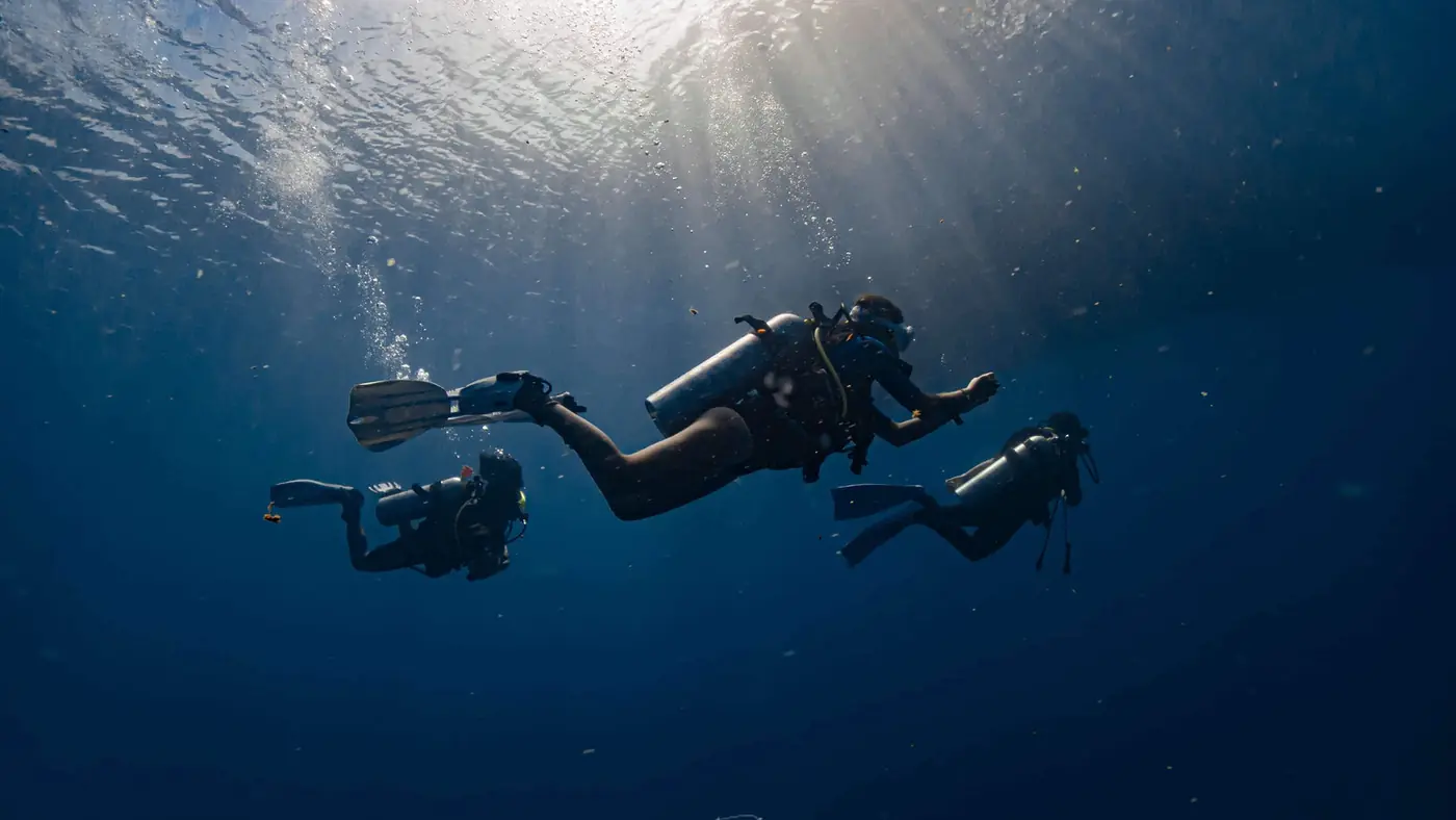 Divers descending through sunbeams off Koh Tao